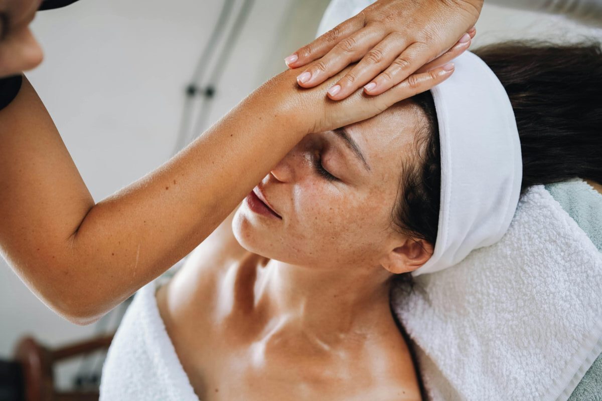 A serene spa experience featuring a woman receiving a calming face massage to promote relaxation and wellness.